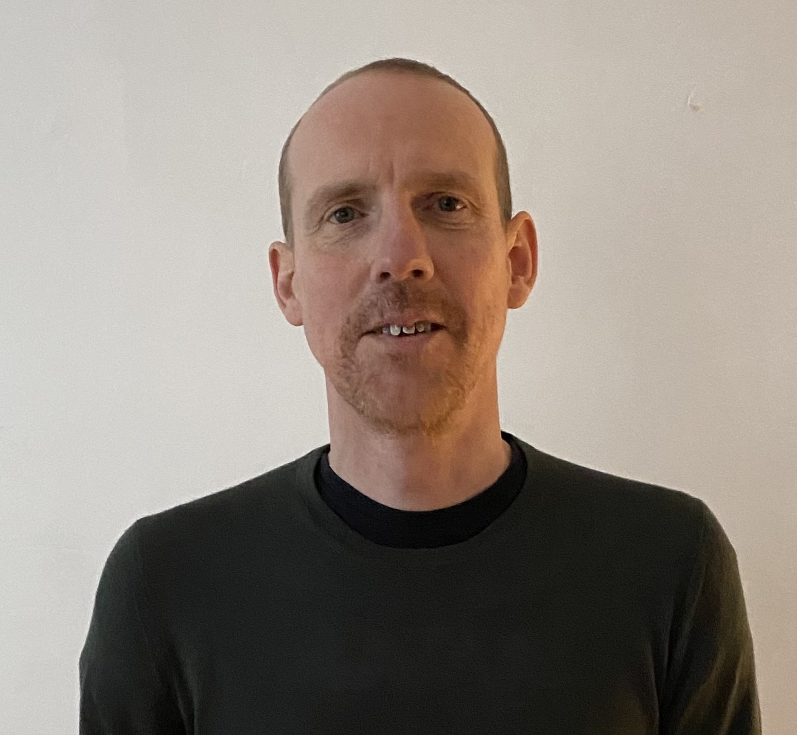 Photograph of white male wearing a black top against a cream background