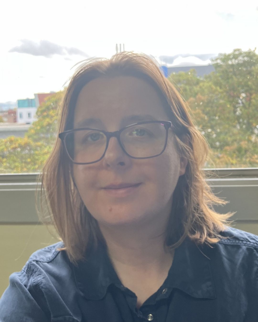 Photograph of a white woman with shoulder length hair, wearing glasses
